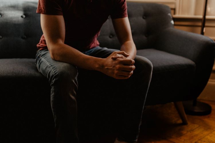 A man in therapy, hands clasped in alcohol rehab Bradford