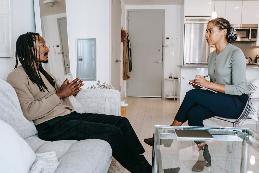 A female therapist talking to a man in a lounge setting