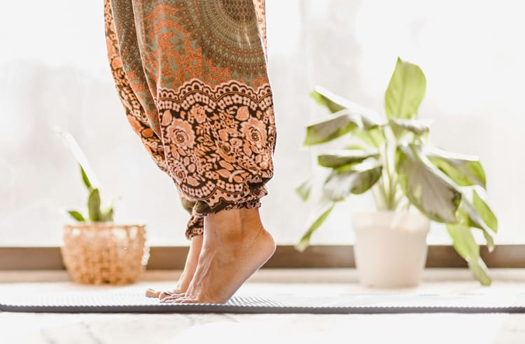 A woman on her toes on a yoga mat who is suffering from gout